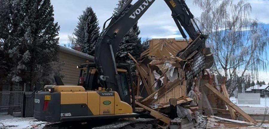 Excavator demolishing a house structure